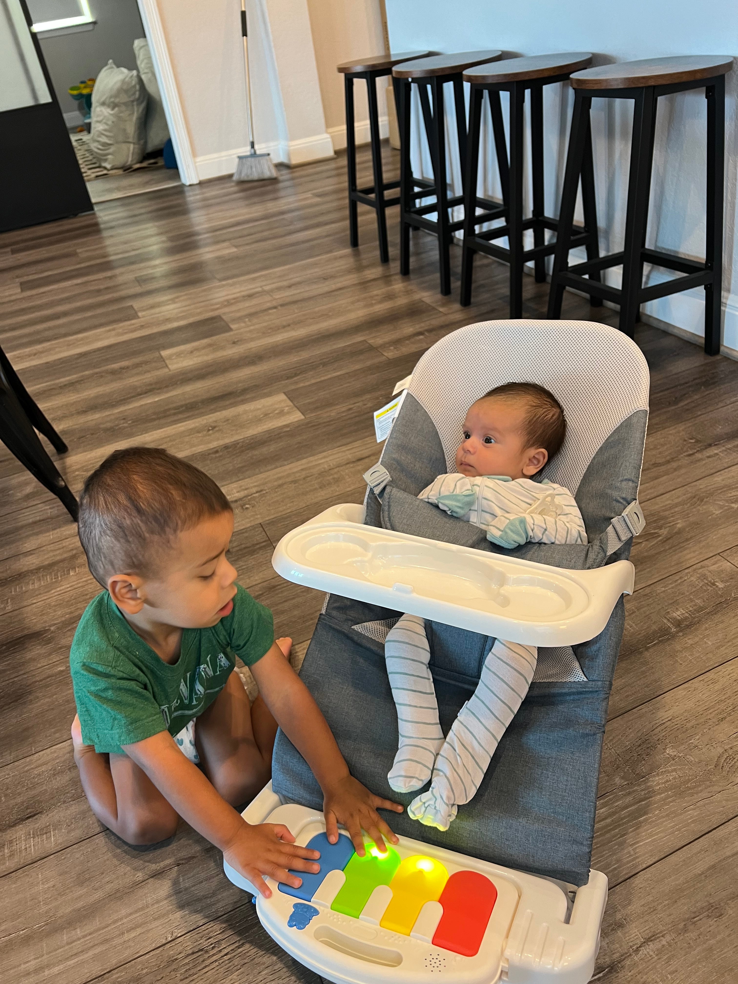 Parent feeding baby on vacation using Montessori baby bouncer chair